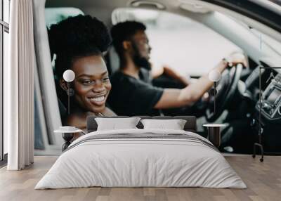 Smiling african couple in car with coffee. Young african girl looking at camera. African man at the wheel drive car Wall mural